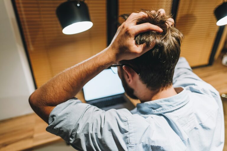 Young stressed businessman in a panic in front of a computer in office.